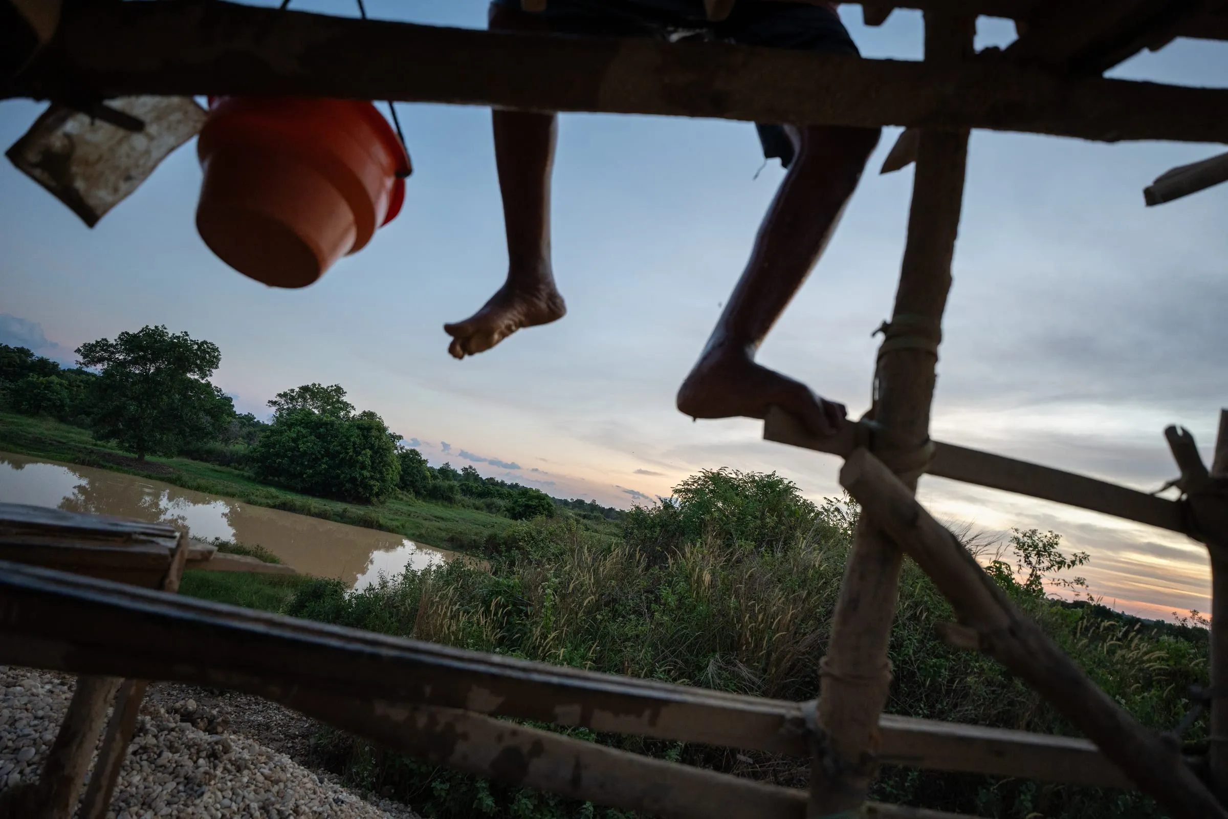 Amin climbs the wooden hoist tower built over the mine shaft. The frame supports ropes and pumps that lift water and gravel from depths of up to ten meters. The gravel is then filtered and washed several times a day in search of diamonds.